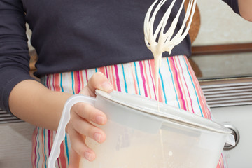 Cooking dough. Girl whips with a mixer