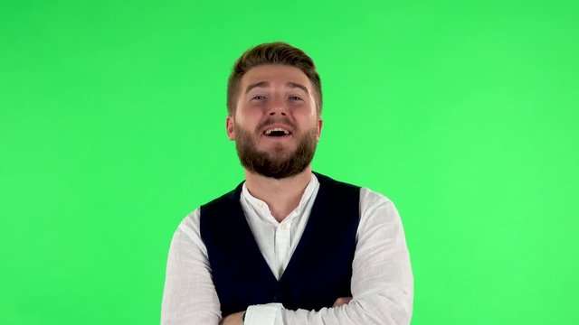 Guy is talking to someone, smiling and shaking his head with assent, showing the like sign. Green screen