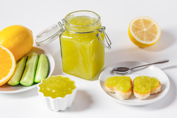 Homemade delicious cucumber jam with lemon and heart shaped toast on white background.