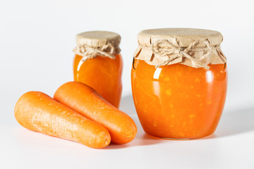 Juicy homemade carrot jam in glass jars on a white background.