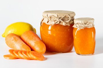 Juicy homemade carrot jam in glass jars on a white background.