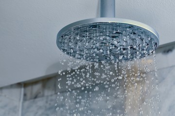 Fototapeta na wymiar Shower turned on, ceiling shower head closeup