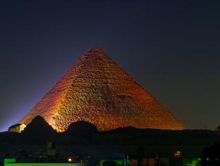 View of the Pyramids of Giza illuminated at night. In Cairo, Egypt