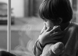 Emotional portrait of upset little boy sitting next to window, Kid sad face,Dramatic photo of...