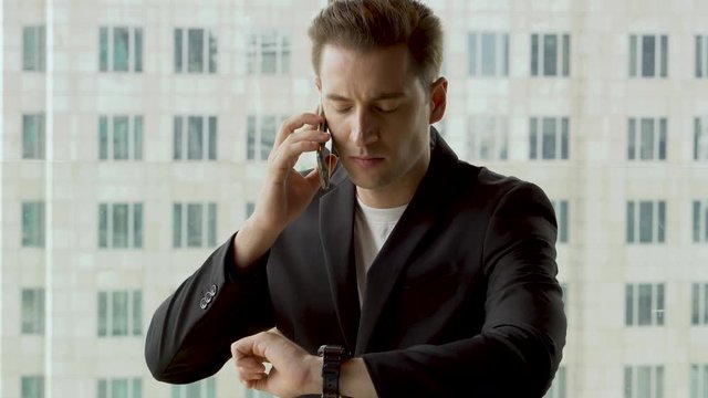 Nervous businessman looking at wrist watch checking time waiting for  business meeting and call speaking by mobile phone follow up customer  or Partners in office. Hurry up . watching time late dating