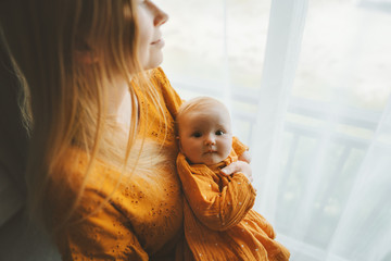 Mother with daughter infant baby family lifestyle mom and child together at home motherhood concept Mothers day holiday mustard colour dress - Powered by Adobe