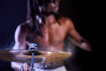 black male with dreadlocks rehearsing on drums before his rock concert, water drops on drums. close-up