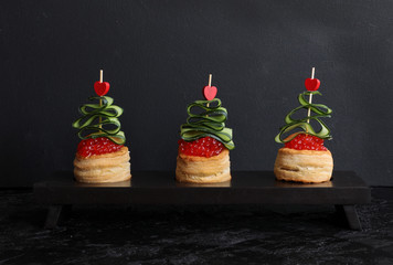 Tartlets with red caviar on the Christmas table, with decorations in the form of a Christmas tree. Christmas and new year snack. Christmas celebration. Selective focus.