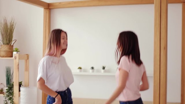 Teen girls lifestyle. Carefree leisure. Two happy female friends enjoying dancing on bed at home.