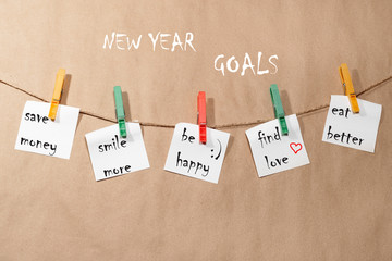 New Year's goals. Stickers hanging on a rope attached with red and green clothespins, on a paper background
