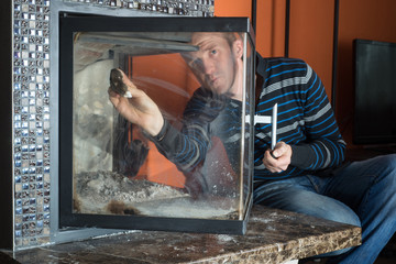 Man wipes the dirty glass of fireplace