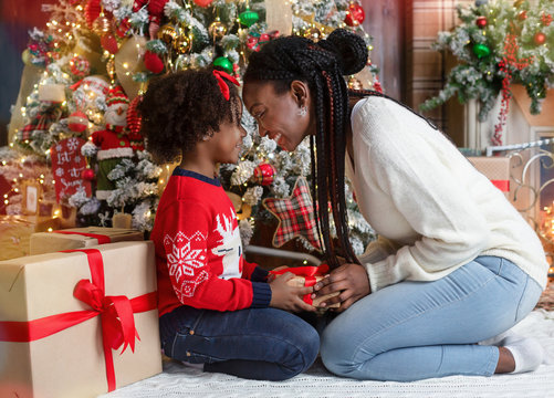 Loving black mother giving Christmas present to her little daughter