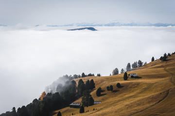 Dolomites, Italy - Lovely cottage on hill, sunny day cloud inversion over hills with autumn colors...