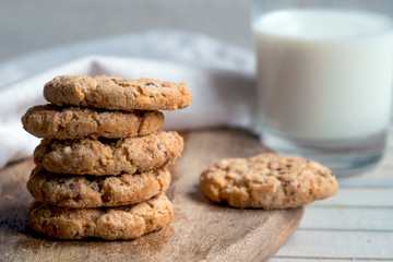 chip cookies and milk on wooden cutting board