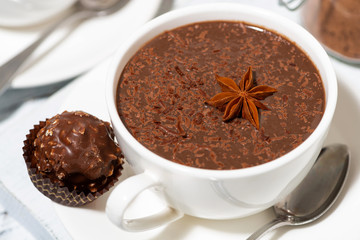 cup of hot chocolate and chocolate candy on white table, closeup