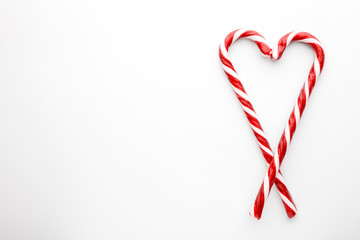 Heart shape made with Christmas candy canes on white background. Minimal composition with...