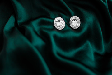 Luxury diamond earrings on dark emerald green silk, holiday glamour jewelery present