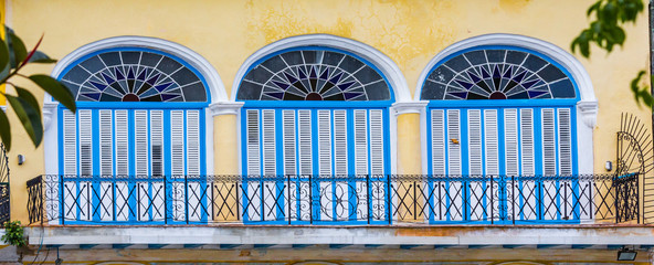 Colorful shuttered windows on bright yellow building in Cuba