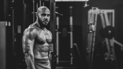 Fototapeta na wymiar Portrait of young healthy muscular man working out with dumbbells in gym, dramatic black and white image