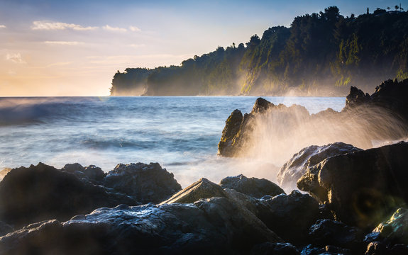 Lava rock shoreline with breaking waves at dawn in Hilo, Hawaii