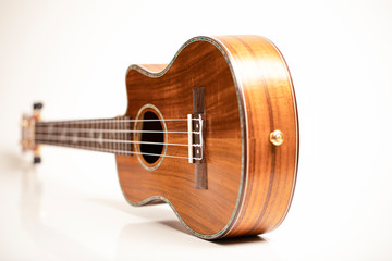 Ukulele on a white background. Hawaiian guitar lies on the table.