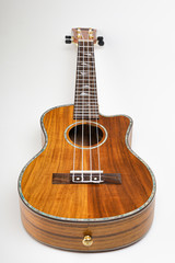 Ukulele on a white background. Hawaiian guitar lies on the table.