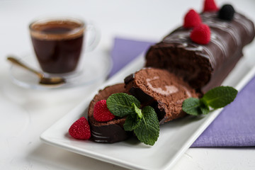 Sliced chocolate roll. Decorated with strawberries. Copy space. Christmas, New Year mood. Breakfast with a cup of coffee. 