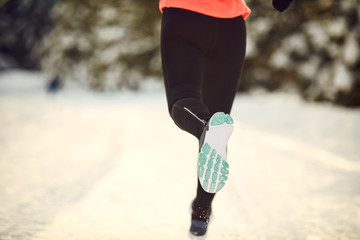 Closeup of girl runner's feet in park in winter