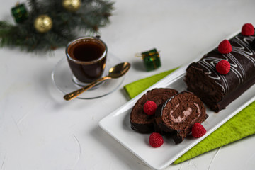 Sliced chocolate roll. Decorated with strawberries. Copy space. Christmas, New Year mood. Breakfast with a cup of coffee. 