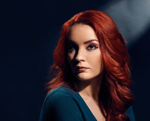 Portrait of beautiful redheaded woman with curly hairstyle and bright makeup