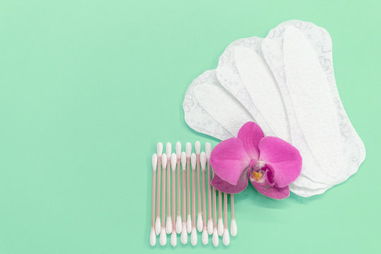 cotton buds, pads, gaskets on a mint background. Orchid flower. Eco-friendly