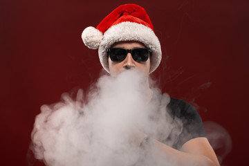 Vaping man in santa claus hat and a cloud of vapor