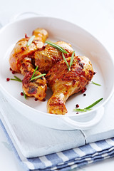 Baked chicken drumsticks with fresh rosemary on bright background.  