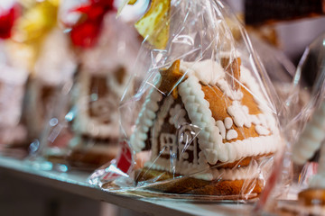 Christmas handmade gingerbread cookies on wooden shelf, small house shaped cake, packed with red and gold bow