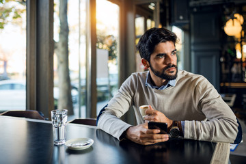 Handsome pretty young man using phone at cafeteriahim