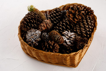 Basket with forest cones on a white texture background. Close-up. The concept of a festive mood.