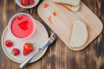 Strawberry jam. Bread and strawberry jam on a wooden table with jar of jam and fresh strawberry. Top view. Making sandwiches with strawberry jam.