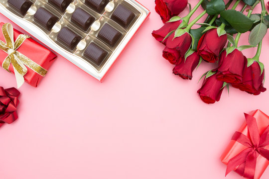 Valentine's Day, red roses, gift boxes and chocolate box with ribbon, over pinkl background flat lay, birthday abstract background with copy space.