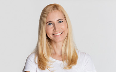 Portrait of beautiful middle-aged woman against grey background