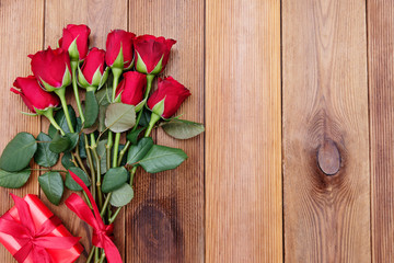 Fototapeta na wymiar Red roses and gift box with ribbon, over wooden background flat lay. Valentine's Day, Birthday abstract background with copy space.