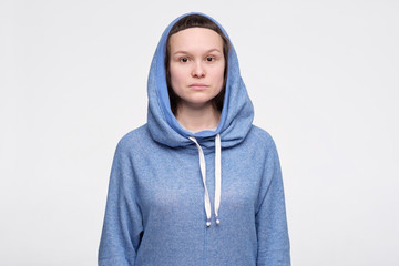 Emotionless, unsentimental phlegmatic caucasian teenager with serious look looking at camera.