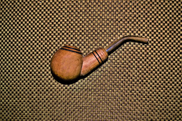 the smoking pipe lies on a brown rag material