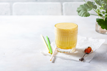 Cup of ayurvedic drink golden almond milk or turmeric latte with curcuma powder on white background. Natural detox beverage with spices.