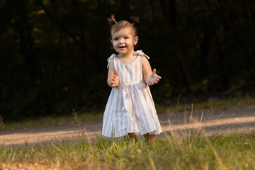 aby girl have fun in the park, running barefoot on the green grass.