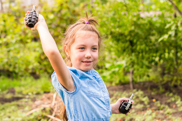 The child learns to throw grenades. Children's combat training. Portrait of a little girl with two...