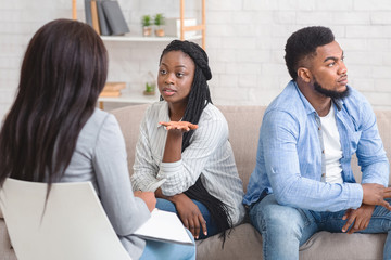 Wife Sitting Next To Her Displeased Husband And Talking To Counselor