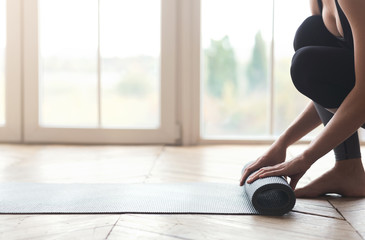 Side view of woman rolling her yoga mat before training