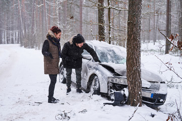 Fototapeta na wymiar Girl shows her boyfriend the damage to his car after the accident. The girl crashed her boyfriend's car. Crashed car after accident in snowy forest