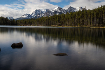beautiful view of mountains above hector lake in banff national park with calm waters