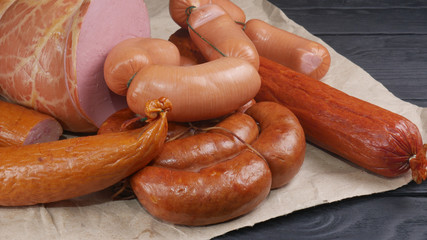 Assorted sausages on a black wooden table laid out on paper